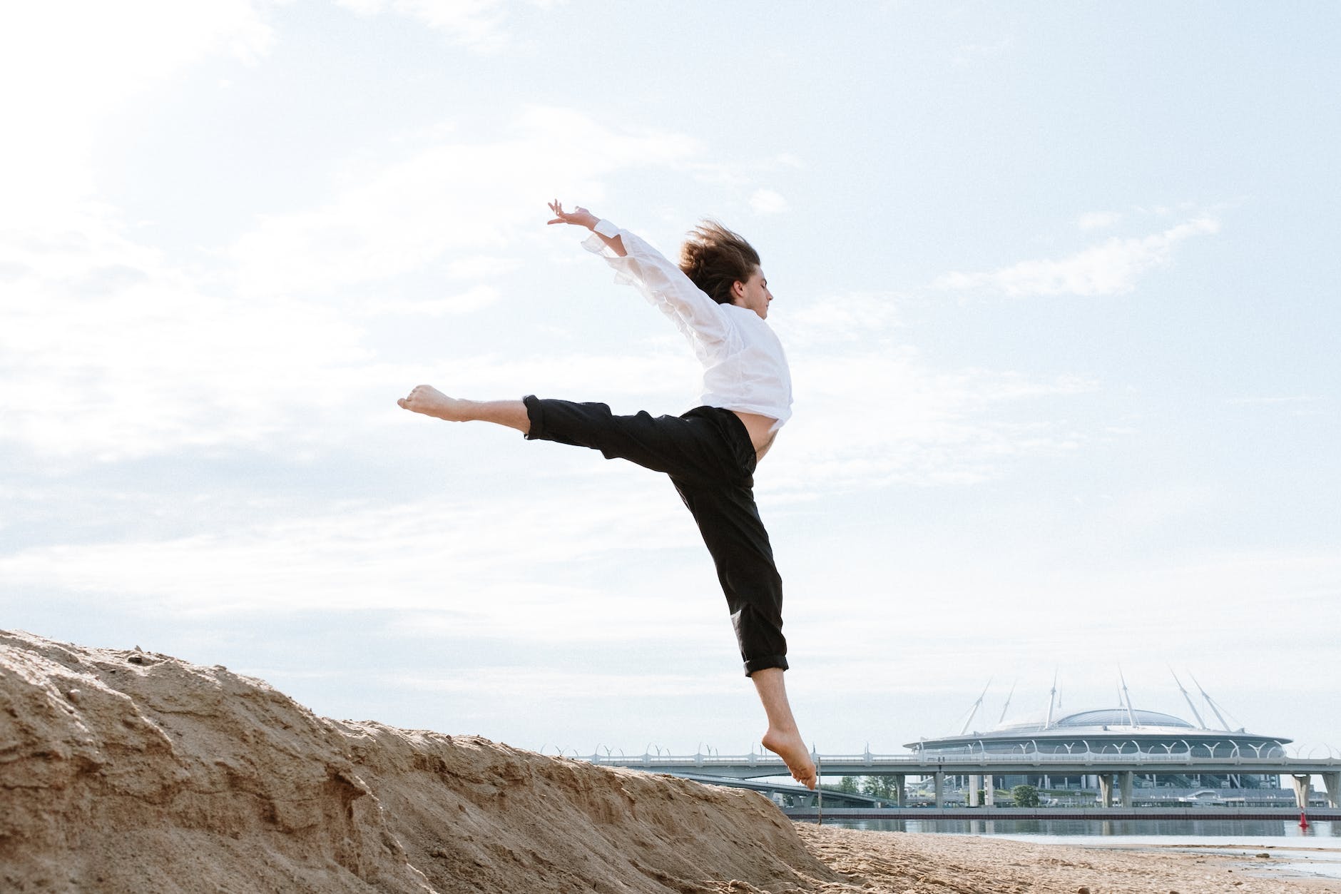 woman in white long sleeve shirt and black pants standing on brown rock formation near body