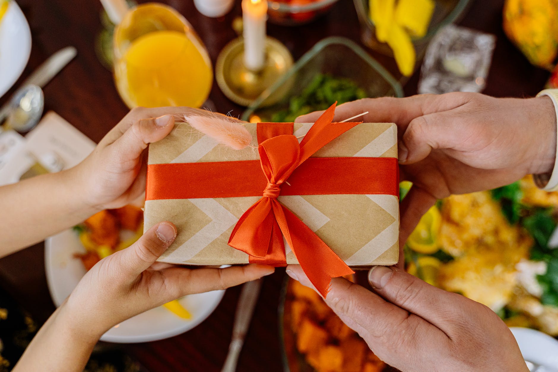 close up shot of two people holding a wrapped gift with a ribbon